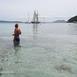 Rear view of shirtless man sailing in sea