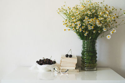 Book, cherries and vase with chamomile flowers. read and rest. cozy spring concept.