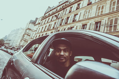 Portrait of man in car against building