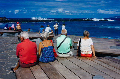 Rear view of people sitting on beach