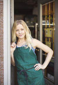 Portrait of confident fashion designer standing at studio doorway