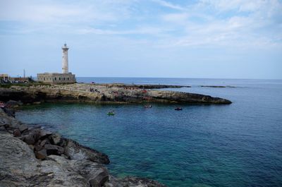 Lighthouse by sea against sky
