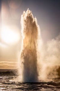 Water splashing in geyser against sky at sunset