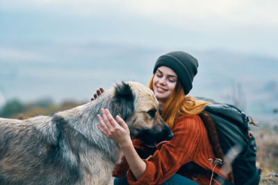 Portrait of woman with dog against sky