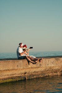 Dad and daughter in santa claus hats eat ice cream on the pier and take selfies