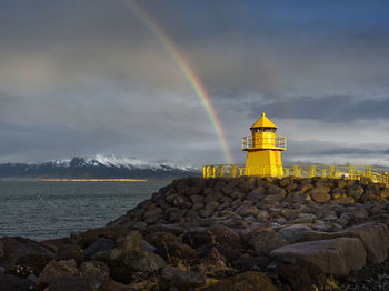 Lighthouse by sea against sky