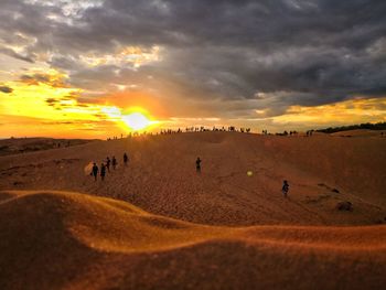 People on beach against sky during sunset