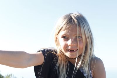 Close-up of smiling girl looking away against clear sky