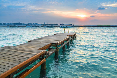 Pier over sea against sky during sunset