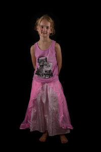 Portrait of young woman standing against black background