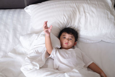 High angle portrait of cute boy lying on bed at home