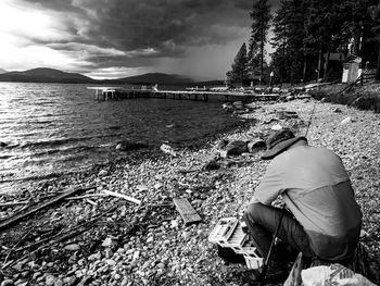 Rear view of man sitting on riverbank