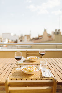 Wine and pasta served on table at building terrace during sunny day