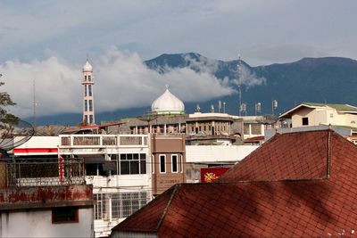 Houses and mosque against cloudy sky