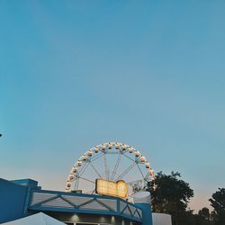 Low angle view of ferris wheel against clear blue sky