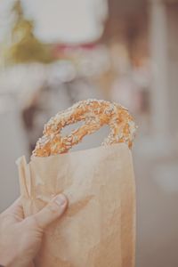 Close-up of hand holding food in paper bag