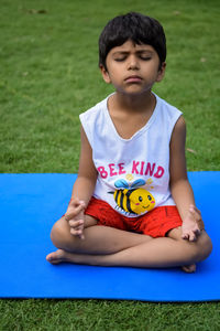 Asian smart kid doing yoga pose in the society park outdoor, children's yoga pose. the little boy
