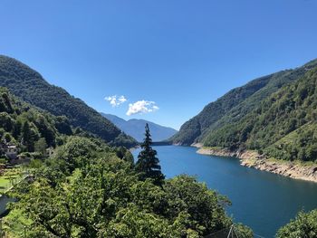 Scenic view of river and mountains against clear blue sky