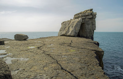 Rock formation on beach against sky