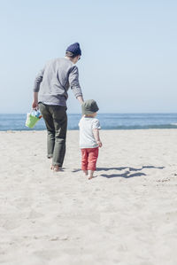 Rear view of father and daughter on beach