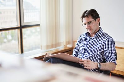 Mature businessman reading document in office