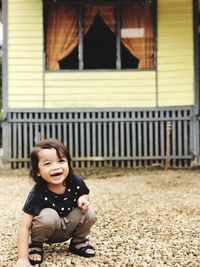 Portrait of smiling boy crouching on footpath