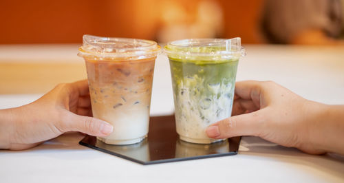 Close-up of hand holding drink on table