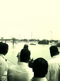 Rear view of silhouette people on shore against clear sky