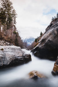 Surface level of stream by rocks against sky