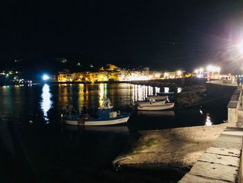 Boats moored in harbor at night