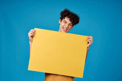 Portrait of smiling young woman against blue background