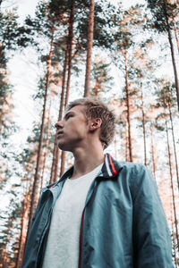 Low angle view of young man looking away in forest