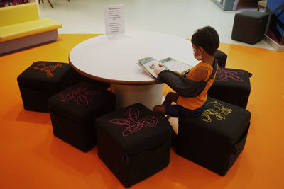 High angle view of boy sitting on table