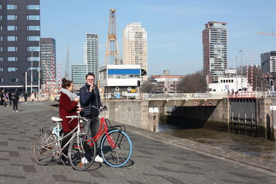 Bicycles parked by canal against buildings in city