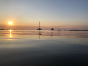 Sailboats in sea against sky during sunset