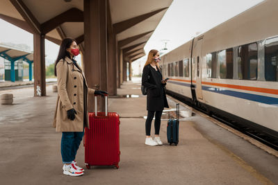 Full length of women wearing mask standing on railroad platform