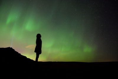 Silhouette woman against background of northern lights 