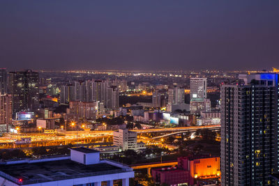 Illuminated buildings in city against sky at night