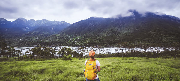 Rear view of man standing on mountain against sky