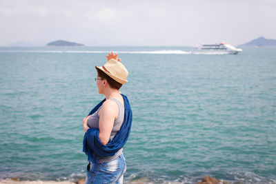 Young woman looking at sea against sky