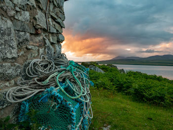 Fishing net by sea against sky during sunset