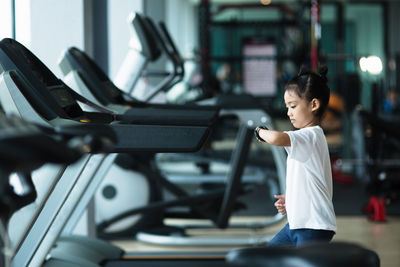 Side view of girl looking at smartwatch in gym