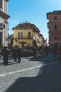 People walking on street against buildings in city