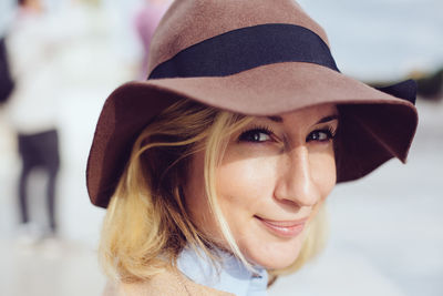 Close-up portrait of smiling young woman wearing hat