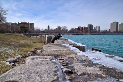 Side view of man standing by lake michigan by city against sky