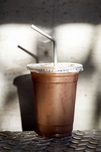 Take away plastic cup of iced black coffee .