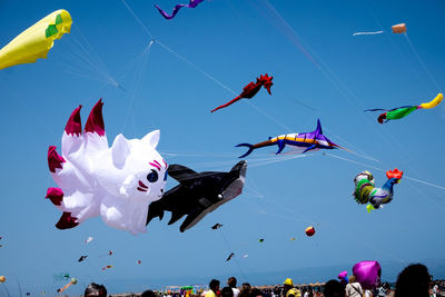 Low angle view of kites flying against blue sky