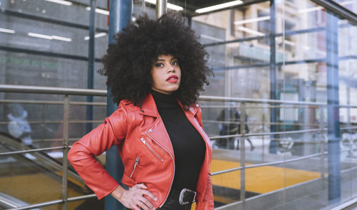 Portrait of beautiful young woman standing against railing