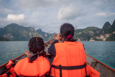 Rear view of women on boat in sea against sky