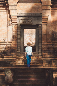 Rear view of woman walking on staircase against building